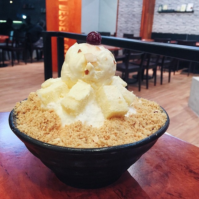 Cheesecake Bingsu - biscuits crumbs beneath and around shaved ice topped with cheesecake pieces and a scoop of vanilla ice cream.