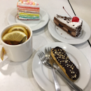 Cakes, chocolate eclair and hot lemon tea