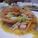 Wok fried assorted seafood with macadamia nuts served in edible nest