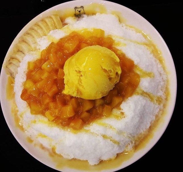 Mango ice cream and cubes with slices of banana over huge mountain of finely shaved ice soaked in sweet milk...