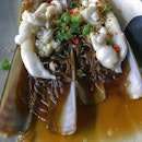 Bamboo clam, steamed with minced garlic and mung bean threads, soaked in superior soya sauce, and dusted with spring onion and chopped chillies.